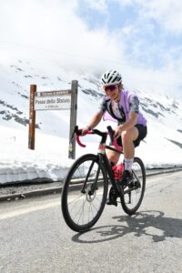 Sportliche Frau beim Rennradfahren am Passo dello Stelvio auf 2758 m Seehöhe – Symbol für Fitness, Energie und Lebensfreude über 40.